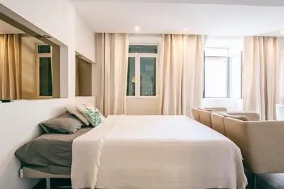 a bedroom with a bed and a chair and a mirror at Funchal City Studio in Funchal