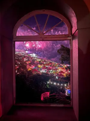 a window with a view of a city with fireworks at Elegant and Relaxing Seaview Apartment with Pool in Funchal