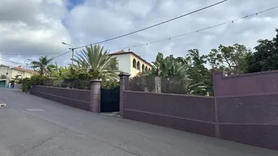 a fence with palm trees and a building at Elegant and Relaxing Seaview Apartment with Pool in Funchal