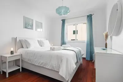 a white bedroom with a white bed and a window at Atlantic Paradise in Caniço