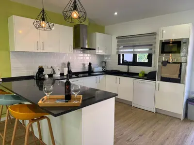 a kitchen with white cabinets and a counter with two wine glasses at D - DELIGHTFUL Cottage with FREE Private Parking in Machico