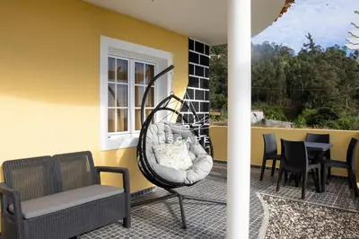 a porch with a swing and chairs on a patio at Feiteiras House by Escape to Madeira in Ponta do Sol