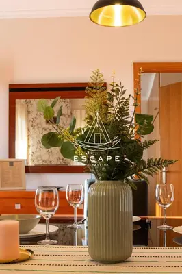 a vase filled with plants on a table with wine glasses at Feiteiras House by Escape to Madeira in Ponta do Sol