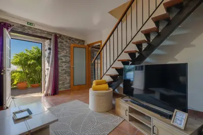 a living room with a large television and a staircase at Casa da Laranja by Holiday Rental Madeira in Tábua
