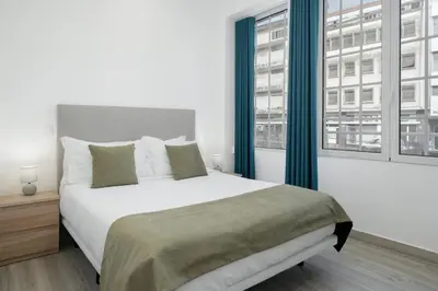 a bedroom with a large bed and two windows at Residência Lord Freitas I by An Island Apart in Funchal
