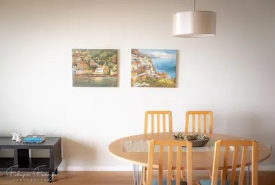 a dining room table with chairs and two paintings on the wall at Funchal bay incredible view with pool in Funchal