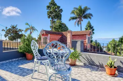 a patio with two chairs and a house at Funchal Hills, a Home in Madeira in Funchal