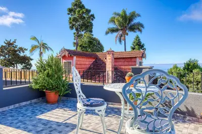a patio with two chairs and a table and a house at Funchal Hills, a Home in Madeira in Funchal