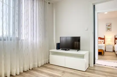 a living room with a television on a white cabinet at Funchal Hills, a Home in Madeira in Funchal