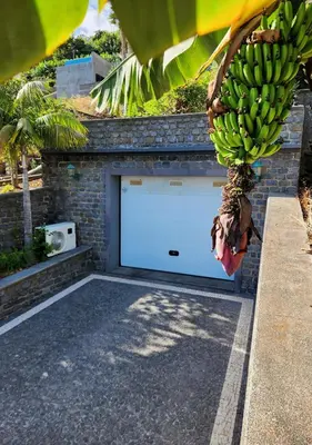 a garage door with a bunch of bananas hanging from a tree at Villa Ocean Wave Calheta - Oversized Pool & Stunning Ocean Views in Calheta
