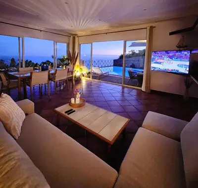 a living room with a couch and a table at Villa Ocean Wave Calheta - Oversized Pool & Stunning Ocean Views in Calheta
