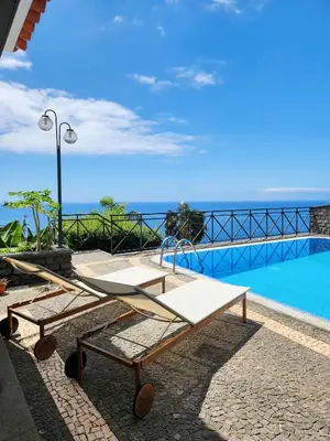 a bench next to a swimming pool with the ocean at Villa Ocean Wave Calheta - Oversized Pool & Stunning Ocean Views in Calheta