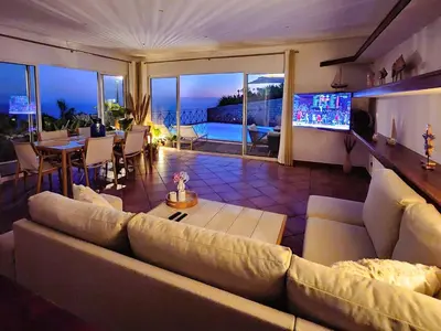 a living room with a large couch and a television at Villa Ocean Wave Calheta - Oversized Pool & Stunning Ocean Views in Calheta