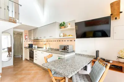 a kitchen with white cabinets and a table with chairs at Raposeira Cottage in Sagres