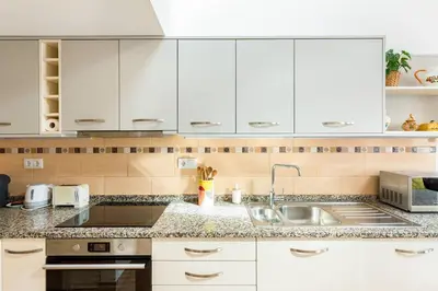 a kitchen with white cabinets and a sink at Raposeira Cottage in Sagres