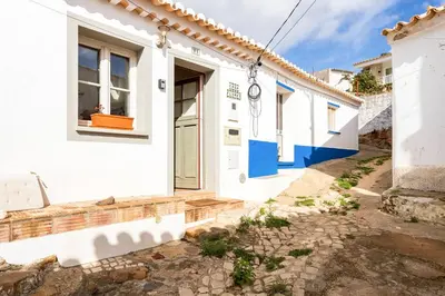 a row of white houses with blue doors at Raposeira Cottage in Sagres