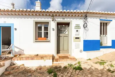 a white house with a blue front door at Raposeira Cottage in Sagres
