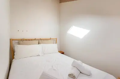 a bedroom with a bed with white sheets and pillows at Raposeira Cottage in Sagres