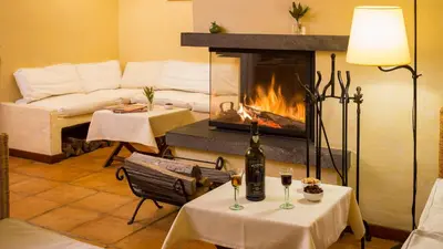 a living room with a fireplace and two tables with wine glasses at Atrio in Estreito da Calheta