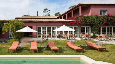 a house with chairs and umbrellas next to a pool at Atrio in Estreito da Calheta