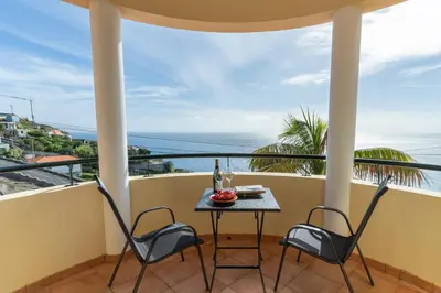 a balcony with a table and chairs and the ocean at Casa Do Dino in Ribeira Brava
