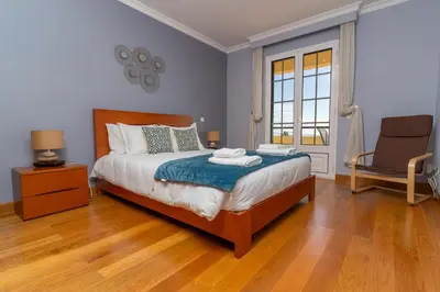 a bedroom with a bed with a chair and a window at Casa Do Dino in Ribeira Brava