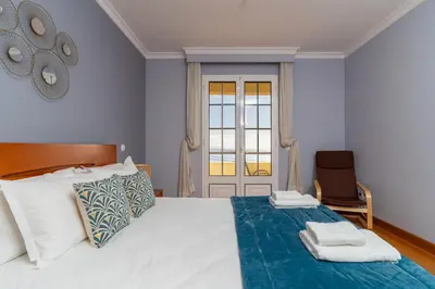 a bedroom with a bed with white sheets and a window at Casa Do Dino in Ribeira Brava