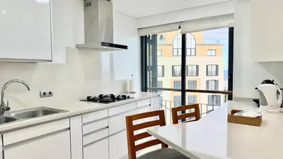a kitchen with white cabinets and a table with chairs at Forum Sky in Funchal