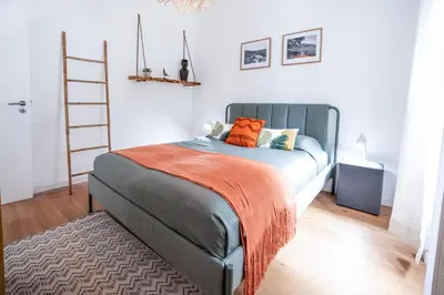a bedroom with a bed with orange pillows and a ladder at CITY OASlS FUNCHAL APARTMENT & STUDIO in Funchal