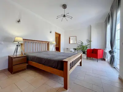 a bedroom with a large bed and a red chair at V4 moderno com Piscina - Burgau in Burgau