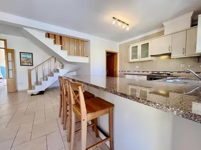 a kitchen with a counter and some chairs in it at V4 moderno com Piscina - Burgau in Burgau