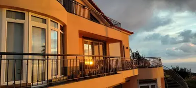 a building with a balcony with a sunset in the background at Beautiful View - Arco da Calheta - Ilha da Madeira in Arco da Calheta