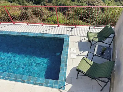 two chairs sitting next to a swimming pool at NEW! casa L, ocean view private pool Villa in Ponta do Sol