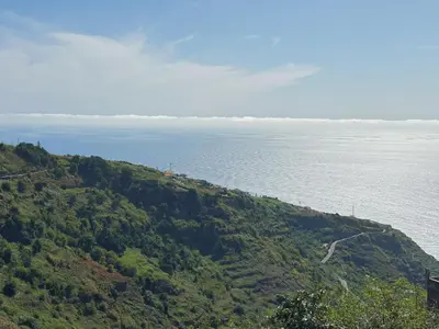 a green hill with the ocean in the background at NEW! casa L, ocean view private pool Villa in Ponta do Sol