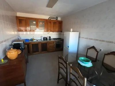 a kitchen with a table and a white refrigerator at Casa do Burgau in Burgau