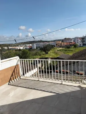 a white railing on a balcony with a view of a city at Casa do Burgau in Burgau