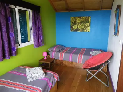 a room with two beds and a chair in it at A charming spot in Estreito da Calheta