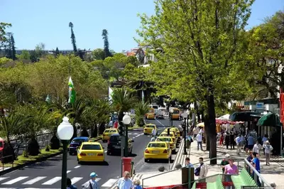 a busy city street with yellow taxis and people walking at Funchal City Yellow Townhouse and Terrace in Funchal