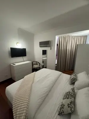 a bedroom with a white bed and a television at Ávila Holidays in Funchal