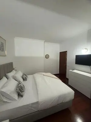 a bedroom with a white bed and a television at Ávila Holidays in Funchal