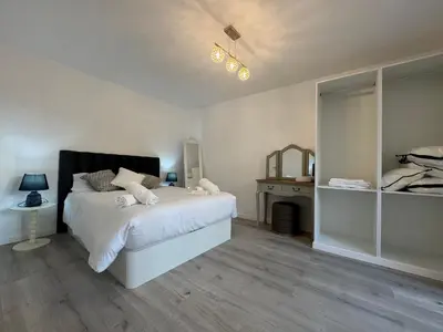 a white bedroom with a bed and a mirror at Charming Seaside Flat in Paul do Mar