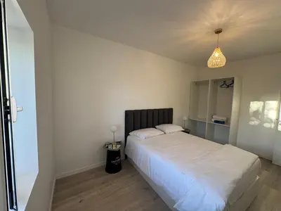 a bedroom with a large white bed and a chandelier at Charming Sunset flat in Paul do Mar