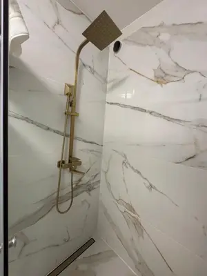 a shower in a bathroom with white marble walls at Charming Sunset flat in Paul do Mar