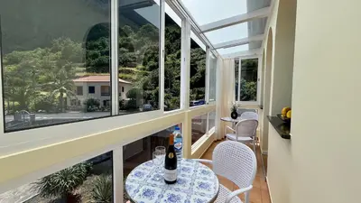 a room with windows and a table with a bottle of wine at Domingos Reis Studio in São Vicente