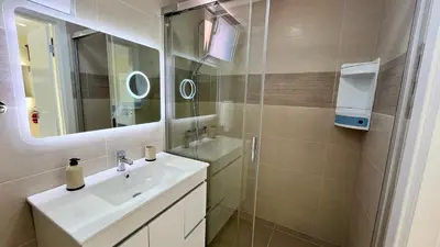 a bathroom with a sink and a mirror and a shower at Domingos Reis Studio in São Vicente