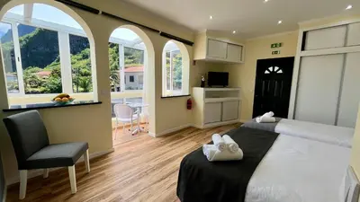a bedroom with a bed and a chair and windows at Domingos Reis Studio in São Vicente