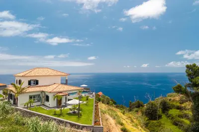 a dining room and living room with a table and chairs at Belo Horizonte in Estreito da Calheta