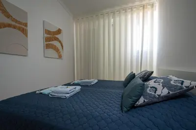 a bedroom with a blue bed with blue sheets and pillows at Lido Oasis Funchal in Funchal