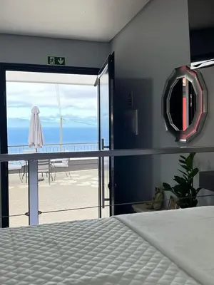 a bedroom with a bed and a view of the ocean at Studio Refúgio in Ponta do Sol