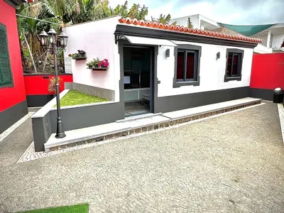 a small white house with a red wall at Studio Refúgio in Ponta do Sol